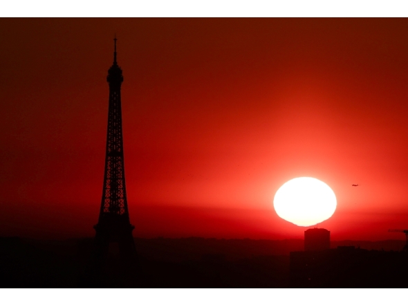 (Files) The sun rises by the Eiffel Tower in Paris on July 1, 2025. (Photo by Thibaud Moritz / AFP)
 