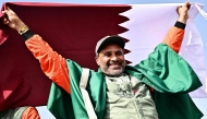 The Dacia Sandriders' Qatari driver Nasser al-Attiyah holds Qatar's flag while celebrating his win in the 48th edition of the Dakar Rally 2026 in Yanbu, Saudi Arabia. (Photo by Giuseppe Cacace / AFP)
 