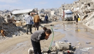 Displaced Palestinians live amongst the rubble and debris of homes and businesses destroyed by the Israeli military in over two years of military strikes on the Gaza Strip enclave, drinks water from a stand pipe, in Jabalia refugee camp, in the northern Gaza Strip on January 17, 2026. Photo by OMAR AL-QATTAA / AFP
