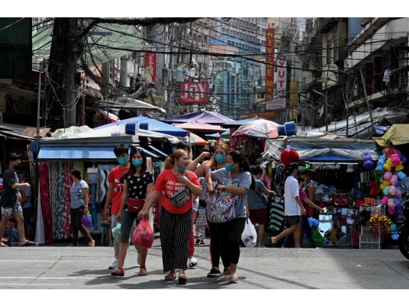 Pedestrians walk as they shop at a market in Manila on January 26, 2022. (Photo by JAM STA ROSA / AFP)