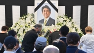 This photo taken on September 27, 2022 shows people offering their respects to former Japanese prime minister Shinzo Abe outside the Nippon Budokan in Tokyo, ahead of his state funeral later in the day. Photo by Yuichi YAMAZAKI / AFP