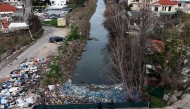 (Files) Local residents walk on a bridge, above plastic trash-filled floodwaters following heavy rains, in Durres, on January 13, 2026. (Photo by Adnan Beci / AFP)