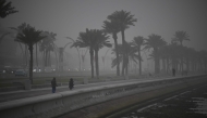 People dressed in winter clothes take a stroll as strong northwesterly winds brought temperatures down in Qatar yesterday.