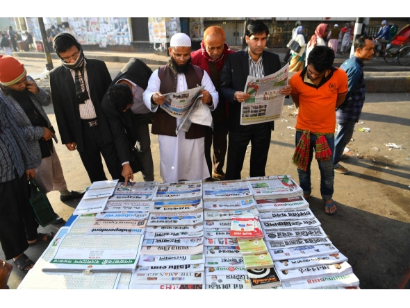 Representational file photo. Bangladeshi people read newspapers carrying headlines of the general election results in Dhaka on December 31, 2018. AFP / Indranil MUKHERJEE