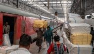 Passengers walk past a cargo compartment on a long-distance train platform at the Chhatrapati Shivaji Maharaj Terminus (CSMT) in Mumbai on February 1, 2026. (Photo by Punit PARANJPE / AFP)