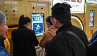 Customers wait to sell their gold jewelry in a Smart Gold Store Machine placed in a shopping mall in Shanghai on January 29, 2026. (Photo by Hector RETAMAL / AFP) 