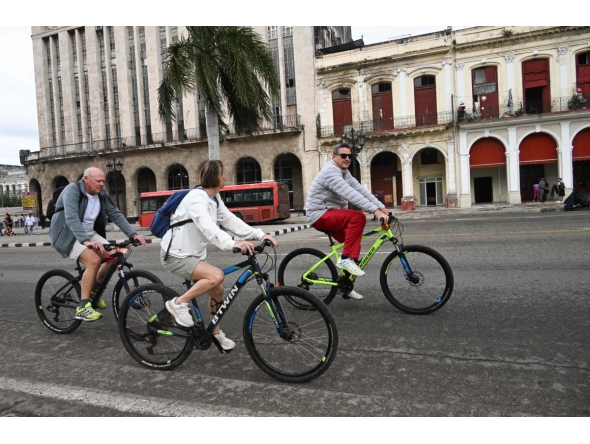 Tourists ride bicycles along a street in Havana on February 2, 2026. (Photo by YAMIL LAGE / AFP)