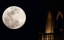 The full moon rises behind a mosque in Doha on February 1, 2026. (Photo by Karim JAAFAR / AFP)