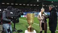 Media representatives are seen by the German Cup trophy displayed prior to the start of the German Cup (DFB-Pokal) quartefinal football match between Holstein Kiel and VfB Stuttgart in Kiel, northern Germany on February 4, 2026. (Photo by Ibrahim OT / AFP) 