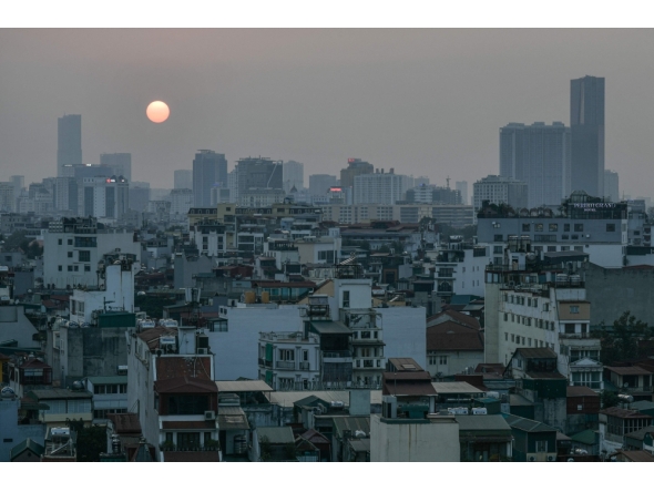 A general view shows the sun setting over the skyline in the old quarter of Hanoi on February 20, 2026. (Photo by Amaury Paul / AFP)