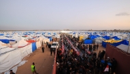Displaced Palestinian families sit at communal long tables as they gather to break the dawn-to-dusk Ramadan fast during Iftar, in the al-Zahara neighborhood, north of the Nuseirat refugee camp in the central of Gaza Strip on February 21, 2026. (Photo by Eyad Baba / AFP)
