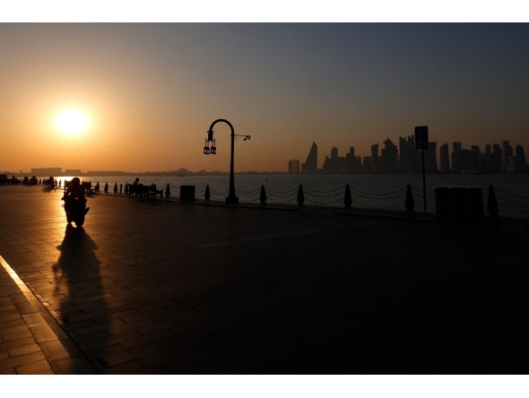 A man is silhouetted by the setting sun as he rides his motorcycle in Doha's Mina district on February 26, 2026. (Photo by Karim Jaafar / AFP)