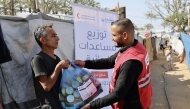 A QRCS representative hands over food aid to displaced people in Gaza. 
