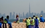 (Files) Workers sit on a wall against the backdrop of the Dubai city skyline on March 11, 2026. (Photo by Giuseppe Cacace / AFP)
