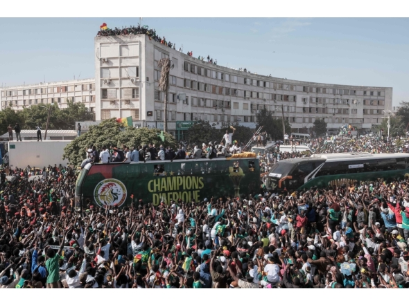 (Files) Supporters cheer as the Senegalese football players ride on a bus during a trophy parade in the streets of Dakar on January 20, 2026. (Photo by Guy Peterson / AFP)