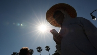 A person wears a hat for shade under the morning sun while walking along The Strand in Redondo Beach, California on March 20, 2026, during a heat wave. (Photo by Patrick T. Fallon / AFP)