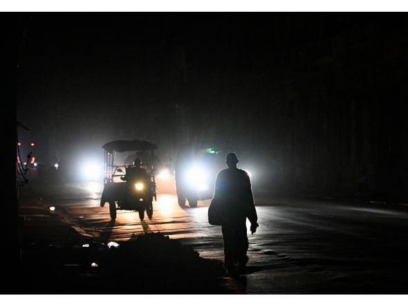A man walks on a street without electricity during a nation wide blackout in Havana on March 21, 2026. (Photo by Yamil Lage / AFP)