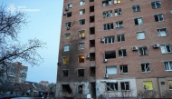 In this handout photograph taken and released by the Ukrainian Emergency Service on March 24, 2026, a woman walks past damaged cars in the courtyard of a damaged residential building following an air attack in Poltava, amid the Russian invasion of Ukraine. (Photo by Handout / Ukrainian Emergency Service / AFP)