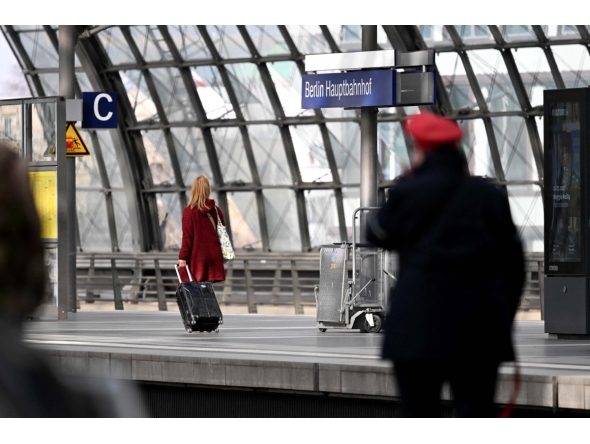 A traveller with suitcase and a train conductor walk along a platform at the main train station (Hauptbahnhof) in Berlin on March 27, 2026. Photo by RALF HIRSCHBERGER / AFP