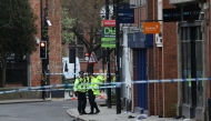 Police officers work near to a variety of personal items seen covering the road inside a cordon set up on Friar Gate in central Derby, central England on March 29, 2026. (Photo by Darren Staples / AFP)