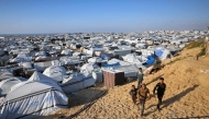 Boys walk past the tents at a makeshift camp for displaced Palestinians in Khan Yunis, in the southern Gaza Strip on April 10, 2026. (Photo by Bashar Taleb / AFP)