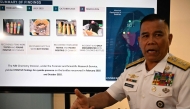 Philippine Navy spokesman Rear Admiral Roy Vincent Trinidad speaks next to a slide presentation of seized yellow bottles suspected to contain cyanide in waters of Second Thomas Shoal in the disputed South China Sea, during a press conference in Manila on April 13, 2026. Photo by Ted ALJIBE / AFP