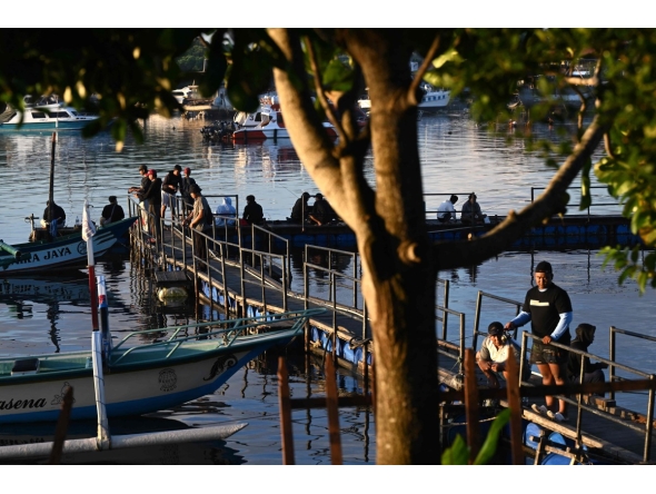 People fish at a pier near Denpasar on Indonesia's resort island of Bali on April 12, 2026. (Photo by SONNY TUMBELAKA / AFP)