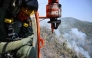 A Thai Department of Disaster Prevention and Mitigation (DDPM) personnel on a firefighting helicopter inspects fire spots to drop water to combat forest fires over Mae On district in the northern Thai province of Chiang Mai on March 26, 2025. Photo by MANAN VATSYAYANA / AFP