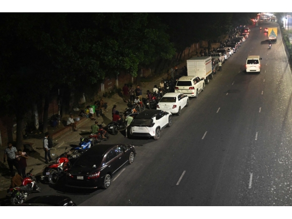People queue up along a road, to refuel their vehicles at a filling station in Dhaka on April 21, 2026. (Photo by MUNIR UZ ZAMAN / AFP)