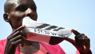 Kenya's Sabastian Sawe poses with his new world record time written on his running shoe at the finish of the 2026 London Marathon in central London on April 26, 2026. (Photo by JUSTIN TALLIS / AFP) / “Restricted to editorial use - sponsorship of content subject to LMEL agreement”.