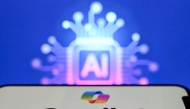 A photo taken on May 7, 2026 shows the letters AI for Artificial Intelligence on a laptop screen (top) next to the logo of the Microsoft's Copilot chatbot application on a smartphone screen in Frankfurt am Main, western Germany. (Photo by Kirill KUDRYAVTSEV / AFP)