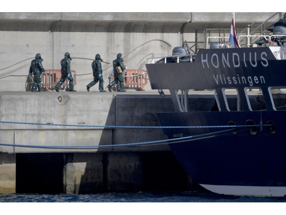 Persons wearing protective suits walk toward the hantavirus-stricken cruise ship MV Hondius docked in the port of Granadilla de Abona on the island of Tenerife in Spain's Canary Islands on May 11, 2026. (Photo by JORGE GUERRERO / AFP)