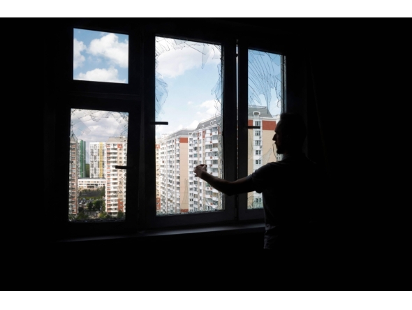 A local resident removes glass shards from a broken window in a residential building following an air attack in Krasnogorsk, Moscow region on May 17, 2026. (Photo by Tatyana Makeyeva / AFP)