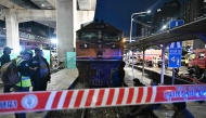 (Files) Officials stand next to the front of a train that collided with a bus underneath Makkasan Airport Rail station in Bangkok on May 16, 2026. (Photo by Lillian Suwanrumpha / AFP)
 