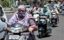 Commuters with their faces covered with cloth ride along a street on a hot summer afternoon in Amritsar on May 23, 2026. (Photo by Narinder NANU / AFP)
 
