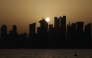 Skyscraper buildings are silhouetted against the setting sun in Doha on May 24, 2026. (Photo by Karim Jaafar / AFP)