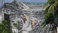 Military personnel with a working dog conduct search and rescue operations at a collapsed building in Angeles City, Pampanga province, north of Manila on May 25, 2026. Photo by Ted ALJIBE / AFP