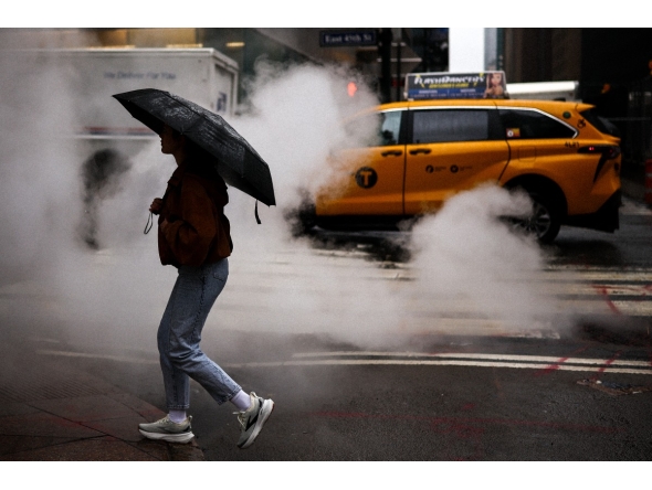 A woman holding an umbrella crosses the street in the rain in New York City, on May 24, 2026. Photo by CHARLY TRIBALLEAU / AFP