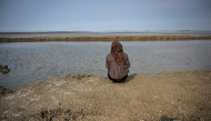 A resident affected by the Lapindo mudflow sits on the embankment in the mud volcano area, marking 20 years since a gas exploration accident triggered a mud flow that inundated more than a dozen villages and permanently displaced tens of thousands of people in Porong, Sidoarjo, East Java province on May 29, 2026. (Photo by JUNI KRISWANTO / AFP)