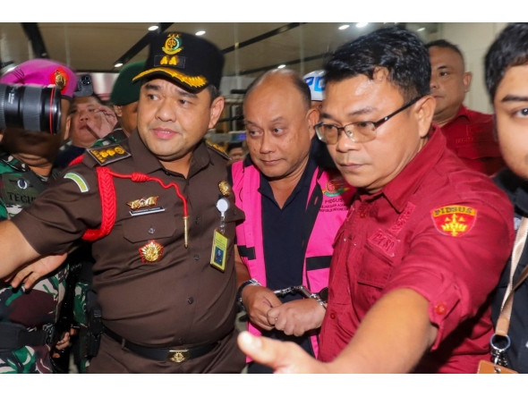 Dadan Hindayana (C), former head of Indonesia's free school meals programme, is escorted by officers from the Attorney General's Office and Indonesian military personnel as he leaves the Attorney General's Office building in Jakarta on June 3, 2026, following questioning over alleged misappropriation in the implementation of the programme. Photo by Diyah Nasution / AFP