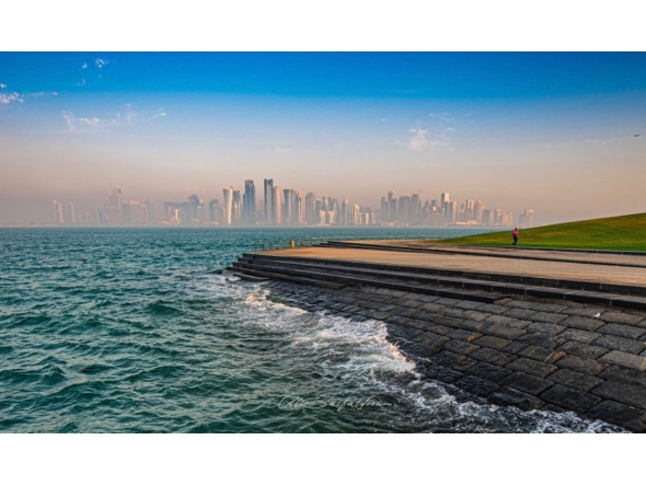 A runner is seen exercising along the Doha Corniche as waves splash along the shoreline e, with Doha's skyline standing prominently in the background. Pic: Qatarweather