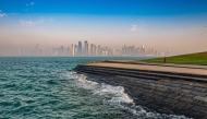 A runner is seen exercising along the Doha Corniche as waves splash along the shoreline e, with Doha's skyline standing prominently in the background. Pic: Qatarweather