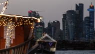 Traditional wooden boats are pictured against the backdrop of illuminated skyscrapers along the Corniche promenade in Doha on May 31, 2026. (Photo by Karim JAAFAR / AFP)
