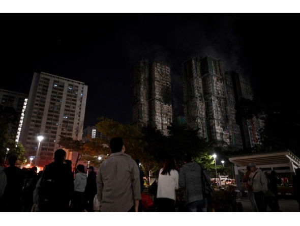 Bystanders look on after a major fire swept through several apartment blocks at the Wang Fuk Court residential estate in Hong Kong's Tai Po district on November 27, 2025. Photo by Philip FONG / AFP