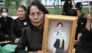 A mourner holds a portrait of late Thai Princess Bajrakitiyabha Mahidol outside the Grand Palace in Bangkok on June 13, 2026. (Photo by Lillian Suwanrumpha / AFP)