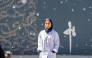 Fatima Alsharshani in front of her mural in Montreal.