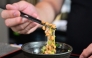 Kenji Suzuki, second-generation owner of Suehiro Japanese Restaurant in Los Angeles, California, lifting natto from a bowl with chopsticks. (Photo by Frederic J. Brown / AFP) 