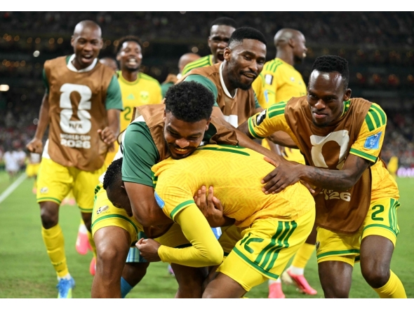 South Africa's forward #12 Thapelo Maseko is hugged by teammates while celebrating scoring his team's first goal. (Photo by Yuri Cortez / AFP)
