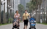 This photo taken on June 29, 2026, shows women pushing strollers with children along a sidewalk in Hanoi. Photo by Nhac Nguyen / AFP
