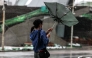 A woman struggles with an umbrella in strong winds and rain as typhoon Bavi passes off northeastern Taiwan in Keelung on July 11, 2026. More than 14,000 people in Taiwan have fled their homes, and many shops remain closed, as a typhoon pounding Japan's remote southwestern islands swept towards China on July 11. (Photo by I-Hwa Cheng / AFP)